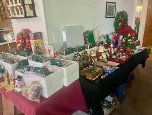Table displaying assorted Christmas decorations, including ornaments, figurines, wreaths, and festive containers.