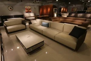 Modern furniture showroom featuring beige and brown sofas, a coffee table, and warm ambient lighting.